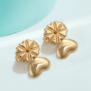 Macro detail of heart-shaped gold earring lifters with polished finish for support