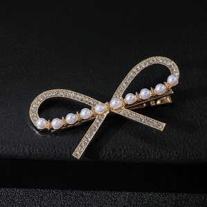 Elegant bow hair clip with gold base, sparkling rhinestones and white pearls on black leather
