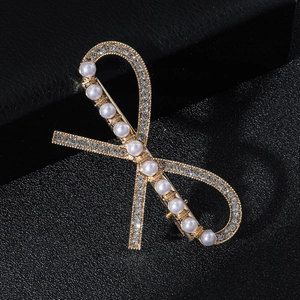 Close-up of golden bow hair clip with white faux pearls and crystals on leather