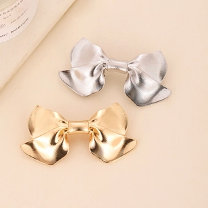 Detail view of gold and silver metal bow hair clips with textured striped finish