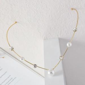 Dettaglio di un'elegante collana choker dorata con tre perle e strass brillanti