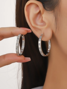 Macro detail of silver hoop earrings with pave-set heart patterns and zircons on a model