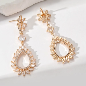 Detailed macro view of gold drop earrings with zircon crystals and floral drop design