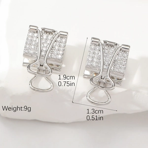 Boucles d'oreilles pince à dessin argentées avec zircons sur décor de pierre blanche
