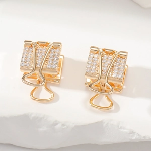 Détail de boucles d'oreilles pince dorées serties de zircons blancs sur socle pierre