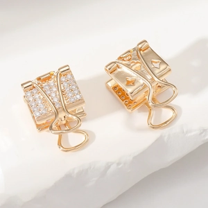 Vue macro de boucles d'oreilles pince à dessin dorées avec zircons et étoile ajourée