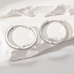 Detailed close-up of silver hoop earrings with micro-pave cubic zirconia on stone base