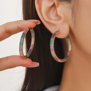 Close-up of rainbow hoop earrings with colorful zircon stones on model's ear