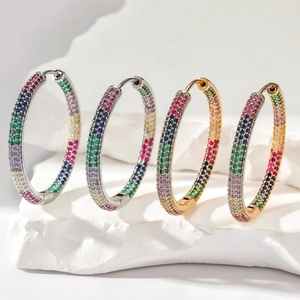 Detailed macro shot of large rainbow cubic zirconia hoop earrings on white stone display
