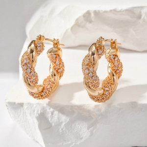 Boucles d'oreilles créoles torsadées en or et zircons sertis sur un fond de pierre blanche