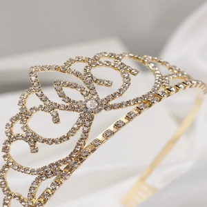Detailed close-up of golden bridal tiara with sparkling white rhinestones and fine filigree