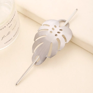 Silver brushed metal hair pin featuring a hollow monstera leaf design in a minimal setting