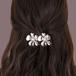 Silver hollow layered flower hair clip with sparkling crystal center on dark wavy hair