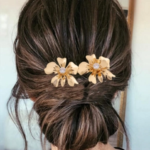 Set of two gold 3D flower hair clips with crystals styled in a low bun updo