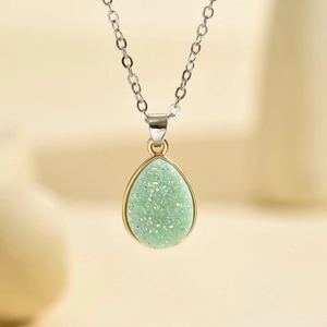 Macro d'un pendentif goutte en résine vert clair avec bordure dorée et chaîne argent