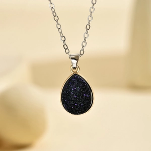 Gros plan d'un collier goutte en résine étoilée bleue et violette avec bord doré