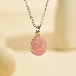Vue détaillée du pendentif goutte en résine rose pailletée avec bordure dorée