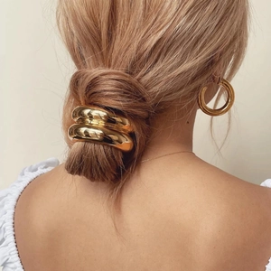 Minimalist golden metal hair tie ring and hoop earrings set on model with low bun hairstyle