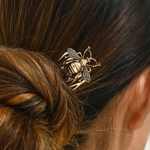Detail of vintage bronze bee hair comb with hollow wings on dark brown hair bun