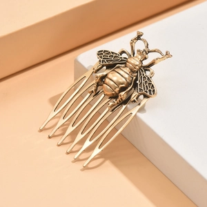 Detail of vintage bronze metal hair comb featuring an embossed bee design and leaf motifs