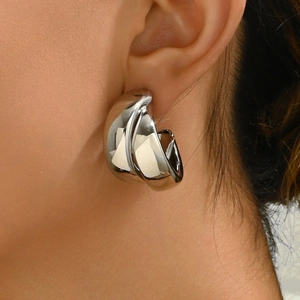 Gros plan sur des boucles d'oreilles créoles en C argentées au fini poli miroir
