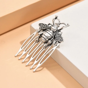 Vintage silver bee hair comb with intricate leaf wing details on minimalist pedestal