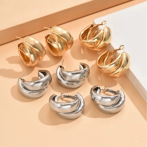Détails macro de boucles d'oreilles créoles superposées en alliage doré et argenté