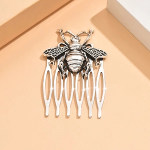 Detail of vintage silver metal hair comb featuring a large textured bee and five prongs