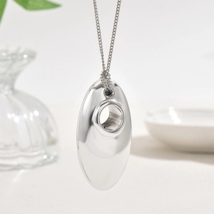 Minimalist silver oval waterdrop pendant necklace with delicate chain on a clean desk