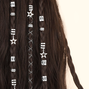 Close-up of silver hollow metal hair rings and star pendants on braided hair styling