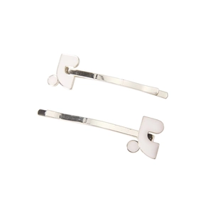 Detailed close-up of two silver metal hairpins with white enamel geometric accents