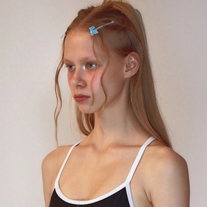 Close-up of a blue puzzle-shaped enamel hair clip worn on model side hair