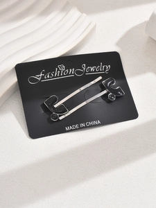 Detail view of two minimalist black enamel bobby pins on display card with silver plating
