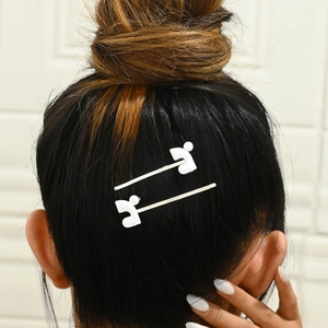 Detail view of two white geometric drip oil hair clips worn on brunette hair in minimalist style