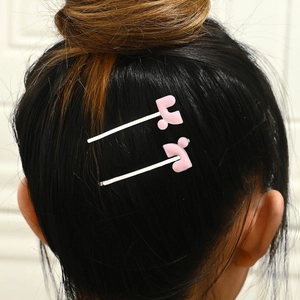 Macro shot of two pink enamel hair clips on hair showing texture and secure grip