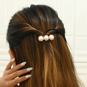 Elegant gold metal hair clip with three white pearls worn on braided brown hair