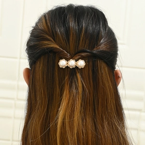 Close-up of elegant gold hair clip with three pearls worn in a half-up hairstyle
