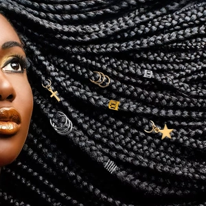 Detailed view of alloy hair charms and rings on textured braids with golden crosses