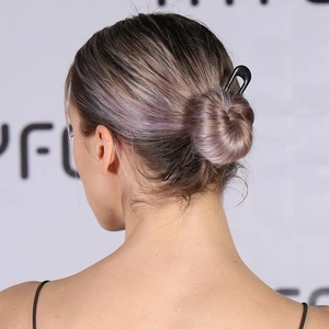 Minimalist black U-shaped hair pin in a matte finish securing a sleek bun hairstyle