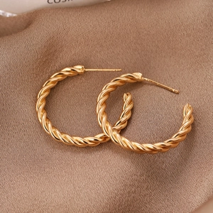 Boucles d'oreilles créoles torsadées dorées style croissant sur fond de soie