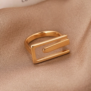 Minimalist rectangular gold ring with a geometric polished design on champagne satin fabric