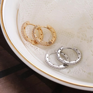 Elegant gold and silver pavé zircon hoop earrings on minimalist ceramic plate background