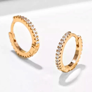 Macro shot of gold huggie hoop earrings featuring a row of sparkling cubic zirconia stones