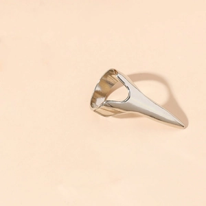 Gepolijste zilveren punk klauwring met scherpe nagelstructuur op een beige achtergrond