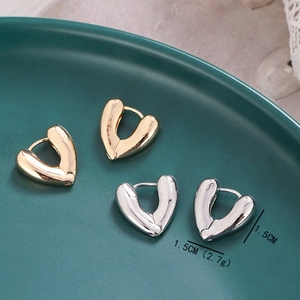 Dettaglio degli orecchini a cerchio a forma di cuore dorati e argentati su vassoio