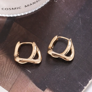 Détail de boucles d'oreilles géométriques dorées torsadées avec finition polie sur magazine