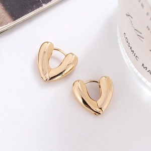 Dettaglio di orecchini a cerchio a forma di cuore in oro lucido su sfondo bianco