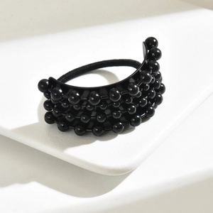 Dettaglio di elastico per capelli nero con quattro file di perline su piastra curva