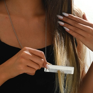 Élégant pendentif peigne argenté pour femmes sur une chaîne en métal poli porté par mannequin