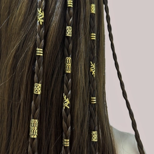 Detailweergave van gouden haarmanschetten en bladringen op gevlochten dreadlocks